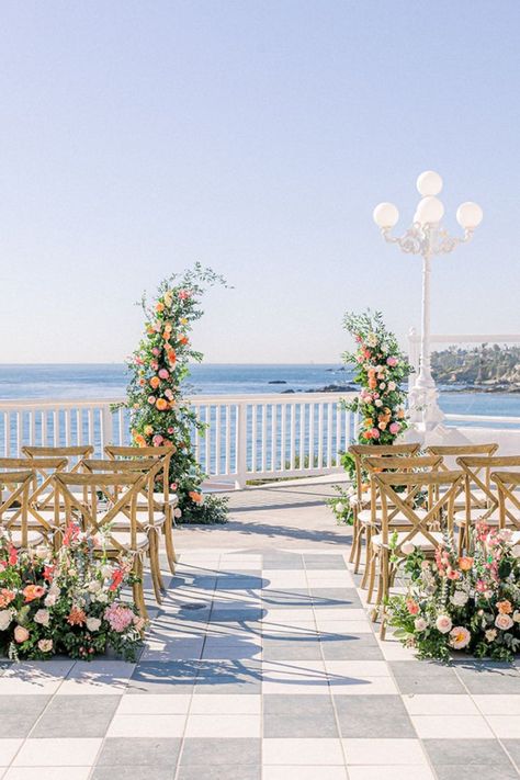 This is a micro/ small/ intimate wedding ceremony setup that has a stunning view overlooking the water and cliffs of the Southern California beach. This beautiful venue is Occasions at Laguna Village in Laguna Beach, CA. This set up is complete with X-back chairs, flower ceremony arch, and other ceremony florals. The main colors for this citrus wedding are shades of pink with a lot of greenery. Beach Backdrop Wedding, Beach Floral Wedding, Floating Arch Wedding, Wedding Ceremony Flower Arch, Beach Ceremony Flowers, Spring Ceremony Decorations, Small Wedding Set Up, Spring Flower Arch, Small Wedding Ceremony Decor