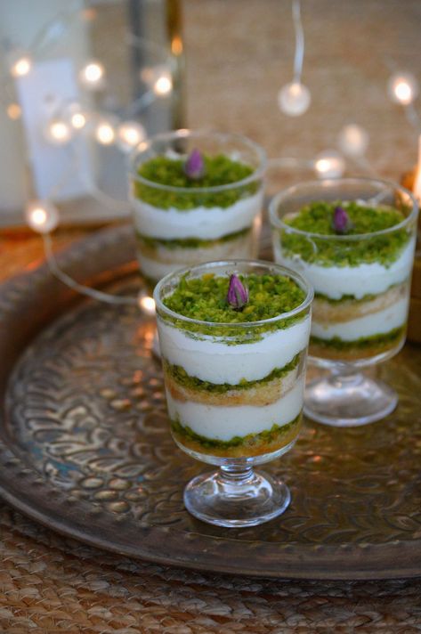 A layered Middle Eastern dessert, Aish el Saraya which contains layers of powdered rusk soaked in sugar syrup, an eggless creamy custard, pistachios and thick cream. This would be the perfect dessert to serve during Eid. We love desserts! And if it is Arabic sweets, we love them even more. You all must be awareRead more Arabic Desserts Middle East, Middle Eastern Party Food, Eid Desserts, Eid Dessert Recipes, Middle Eastern Dessert, Cups Recipes, Eid Sweets, Arabic Sweets Recipes, Lebanese Desserts