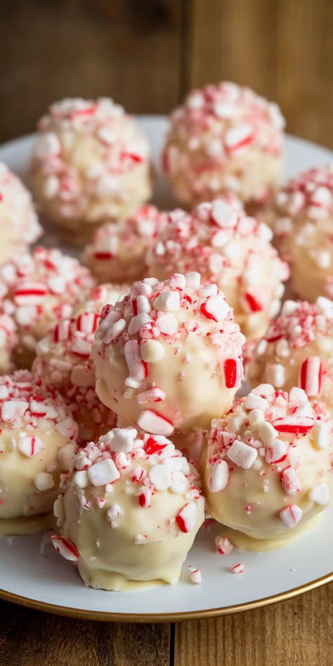 Embrace the holiday spirit with these delightful Peppermint Bark Snowballs! Soft, chewy, and packed with chocolatey goodness, these snowy treats are coated in a sweet white chocolate and sprinkled with crushed candy canes for the perfect festive touch. No Bake Peppermint Snowballs, White Chocolate Peppermint Truffles, Snowman Treats For School, Peppermint Balls Christmas, Dessert Recipes Holiday, Individual Christmas Treats, Peppermint Bark Snowballs, Peppermint Christmas Candy, Peppermint Snowball Cookies