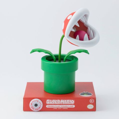 Brighten up your room, gaming den or living space with this collectible Super Mario Mini Piranha Plant Posable Lamp. Complete with a fully posable green stalk, you can position the flexible Venus fly trap style Piranha Plant head to shine bright white LED light from its mouth to wherever it is most needed. Gamers of all ages will want to own this fun and practical desktop light which stands at 6" tall and is anchored by a green plant pot shaped base. Powered by 3x AAA batteries (not included), y Nintendo Room, Green Plant Pot, Trap Style, Room Gaming, Gamer Decor, Piranha Plant, Spring Wedding Guest, Venus Fly Trap, Plant Lighting