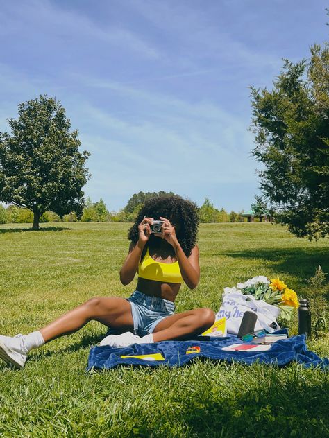 Black woman with curly hair outdoors at picnic with yellow bralette and mom shorts with canvas shoes holding vintage camera taking pictures pointed at camera Picnic Outfit Shorts, Picnic Outfit Ideas Black Women, Picnic Shorts Outfit, Outfit Ideas Spring Black Women, Picnic Outfit Black Women, Park Photoshoot Ideas, Picnic Photoshoot Ideas, City Outfit Ideas, Picnic Shoot