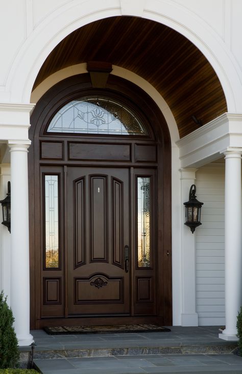 A beautiful wooden arch accentuates the curved window above the front entrance. Arch Window Above Front Door, Arch Top Front Door, Curved Door Design, Main Door Arch Design Entrance, Arch Main Door, Curved Ceiling, Curved Door, Oval Door, Arched Front Door