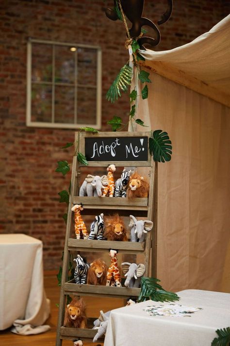 Here is a fun safari jungle party "Adopt a Pet" activity for kids. We set up a shelf with stuffed safari animals and wrote "Adopt Me!" on the chalk board. The guests then chose a safari animal that they wanted to adopt and took it home with them as a party favor. We loved how simple, but fun this activity was for all the kids. Check out our blog for more safari party activities! Safari Theme Birthday Party, Safari Birthday Party Decorations, Jungle Theme Birthday Party, Animal Themed Birthday Party, Zoo Birthday Party, Jungle Thema, Animal Party Favors, Wild Birthday Party, Boys First Birthday Party Ideas