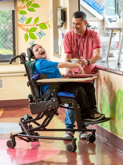 A boy sitting in a Rifton Activity Chair, laughing, with his therapist standing nearby Physio Clinic, Hip Dislocation, Gait Training, Adaptive Equipment, Spy Gear, Disabled Children, Structure And Function, 2025 Vision, Catch Phrase