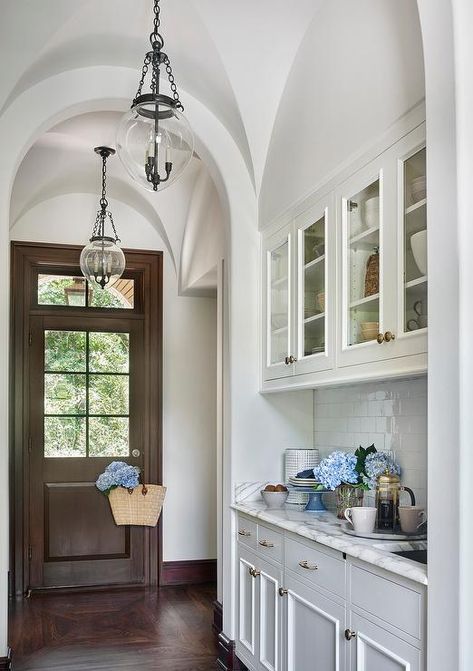 Stunning butler's pantry features a barrel ceiling dotted with Small Amphora Bell Jar Pendants illuminating glass front upper cabinets and white bottom cabinets paired with white marble countertops and a white glazed tiled backsplash laid out in a brick pattern. Pantry Features, Butler Pantries, Dining Room Built Ins, Colored Kitchen, Subway Backsplash, Barrel Ceiling, Built In Cabinet, Beach House Kitchens, Butlers Pantry