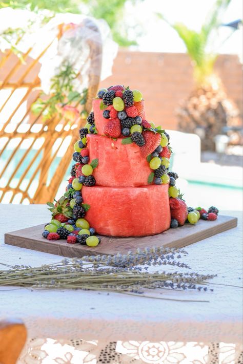 A three tiered cake made out of watermelon and adorned with grapes, blueberries, raspberries,  strawberries, and mint. Watermelon Baby Shower Cake, Summer Baby Shower Food Ideas, Summer Baby Shower Food, Summer Baby Shower Ideas, Baby Shower Food Ideas, Summer Baby Shower Themes, Shower Food Ideas, Baby Shower Watermelon, Baby Shower Fruit