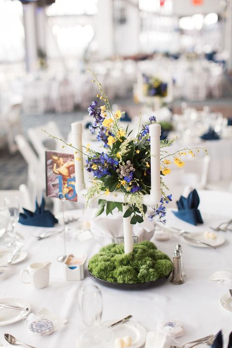 In keeping with the football theme, centerpieces at the reception were goalposts. Ashley's dad made the goals out of PVC pipe. The goals were displayed in moss to resemble the field, and they were decorated with blue and yellow flowers to add a pop of color. Football Themed Wedding Reception, Sports Themed Wedding Reception, Blue Wedding Flower Arrangements, Football Banquet Centerpieces, Penn State Wedding, Ashley Bennett, Blue Wedding Flower, Moss And Flowers, Football Wedding Theme