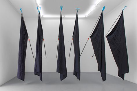 "A series of black flags hung from gardening tools, displaying text by Gilbert Simondon" Claire Fontaine Revolution Symbol, Flag Hanging, Pole Art, Jasper Johns, Conceptual Artist, Flag Art, Installation Design, Black Flag, Pattern And Decoration