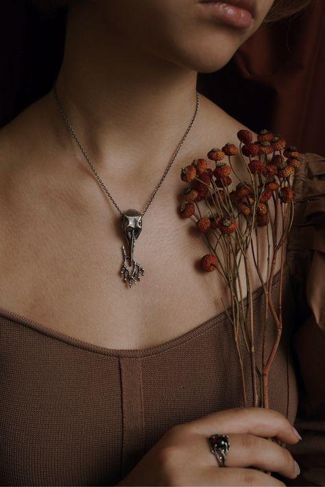 Heavy silver skull holding a branch full of berries. Wiccan aesthetic, Modern witch aesthetic, Witchcore, Whimsigothic aesthetic, Designer witchcore jewelry, Vintage wiccan jewelry, Nature inspired jewelry, Dark fashion aesthetic, Witchy fashion photography, Vintage fashion photography, Vintage twig pendant, Vintage branch pendant, Wild nature pendant, Vintage style pendant, Designer bird scull pendant, Designer raven scull pendant, Dark forest aesthetic, Fairycore aesthetic, Jewelry editorial Vintage Witch Jewelry, Dark Silver Jewelry Aesthetic, Forest Witch Jewelry, Dark Jewelry Photography, Witch Jewelry Aesthetic, Witchcore Jewelry, Dark Fashion Aesthetic, Modern Witch Aesthetic, Wiccan Aesthetic