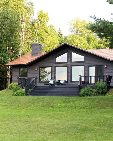 Dark house exterior with grey brown siding and black windows and soffit. Love the black deck and copper metal roof! Such a dark and moody house exterior, with sparkle! #darkhouseexterior #houseexterior #copperroof #blackwindows Lake House Exterior, Dark House Exterior, Lattice Deck, Behr Exterior Paint, Deck Skirting, Deck Makeover, Lake Houses Exterior, Black Deck, Brown Roof