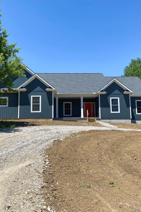 Home exterior with rich Sea Slate board & batten siding, white trim, and a front door painted Raucous Orange! Midnight Blue Board And Batten Siding, Blue Board And Batten House Exterior, Sea Slate Vinyl Siding, Navy Blue Ranch House Exterior, Navy Siding Exterior, Blue Ranch House Exterior, Blue Board And Batten Exterior, Board And Batten Siding Colors, Board Batten Siding