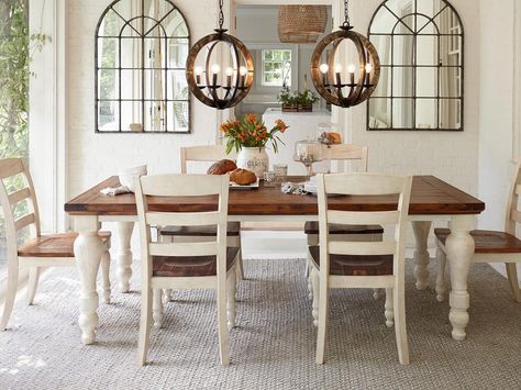 This farmhouse table can be dressed up for a dinner party or Sunday brunch. A timeworn white finish softens the darker wood on the table and seats. Two chandeliers and a neutral rug brighten the room. Off White Dining Table, White And Brown Dining Table, Vintage Dinner Table, Farmhouse Dinner Table, Rustic Farmhouse Dining Room, Farmhouse Style Dining Room, Dining Light, Farmhouse Table Plans, Wooden Kitchen Table