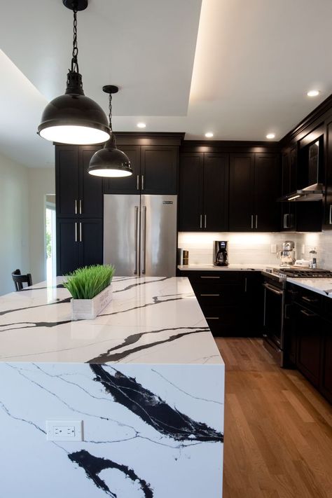 Black kitchens are a popular new design trend we can't get enough of. The black cabinets paired with the marble waterfall countertops make this feel ultra luxurious. Waterfall Countertop Island, Black Kitchen Cabinets Ideas, White Marble Kitchen Island, Kitchen Marble Top, Black Kitchen Ideas, Professional Kitchen Design, Black Marble Countertops, Marble Kitchen Island, White Marble Kitchen