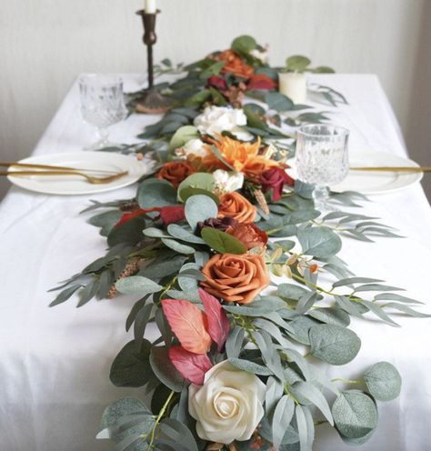 The realistic and natural flowers perfectly blend with eucalyptus leaves and willow, helping to create a romantic ambiance. Eucalyptus Garland Centerpiece, Orange Flower Garland, Eucalyptus Runner, Sweetheart Table Centerpiece, Garland Centerpiece, Table Garland, Flowers For Wedding, Banquet Table, Willow Leaf