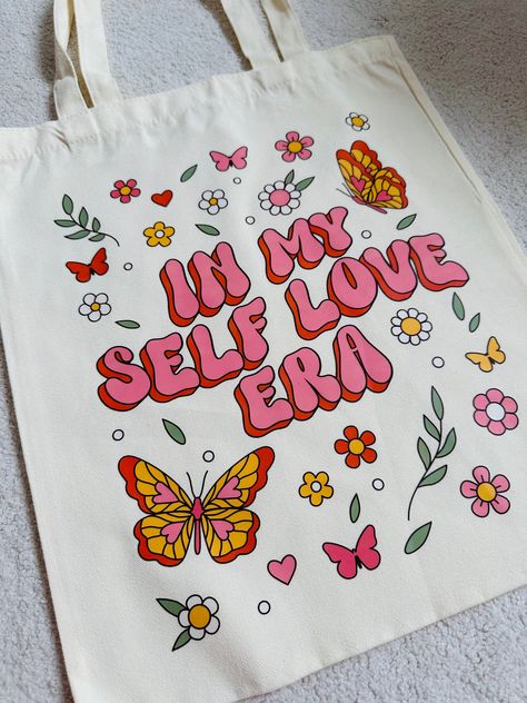 Carry your self love in style with our large Self Love Era Shopper Tote Bag. Perfect for your laptop or a day of shopping, this bag is both functional and fashionable. Size: 37x45cm Material: Canvas Care instructions: Wash inside out on a cold wash Use a mild detergent Opt for a gentle cycle Avoid fabric softeners Iron inside out on a low heat Air drying is preferred If using tumble dryer, dry inside out on a low heat Tote Bag Inspo Painting, Cloth Painting Ideas, Tote Bag Ideas Design, How To Make A Tote Bag, Paint Tote Bag Ideas, Canvas Tote Bag Painting, Cool Tote Bag Design, Cute Tote Bag Design, Totebag Painting