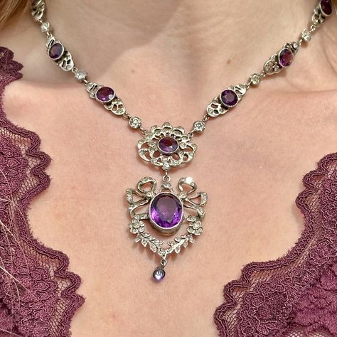 New in! A magnificent antique Edwardian paste lavaliere necklace consisting of ornate silver links leading to a spectacular open-work dropper pendant featuring pretty bow and floral motifs. Each link is bezel set with a large purple paste and accompanied by smaller clear pastes that together simulate amethysts and diamonds. The antique necklace dates to the early 1900s and has remained in excellent condition. It’s held by a safety chain and a flower-shaped box clasp at the end topped with f... Edwardian Necklace, Antique Necklace, Amethyst Necklace, Antique Jewellery, Bezel Setting, Floral Motif, Silver Necklaces, Amethyst, Chain