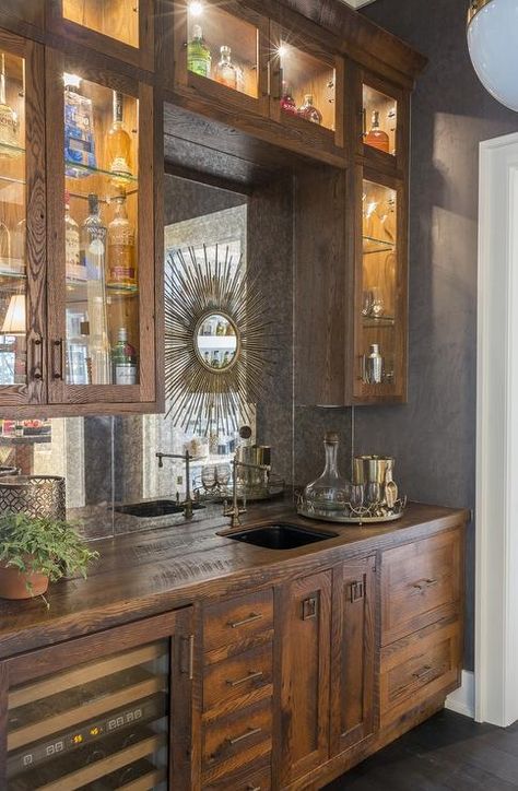 Rustic wet bar features rustic cabinets fitted with a glass-front wine cooler paired with distressed wood countertops fitted with a bar sink and vintage style swing-arm faucet. Mirror Tile Backsplash, Antique Mirror Backsplash, Palmetto Bluff Homes, Mirrored Backsplash, Rustic Sink, Farmhouse Backsplash, Beadboard Backsplash, Mirror Backsplash, Dark Wood Cabinets