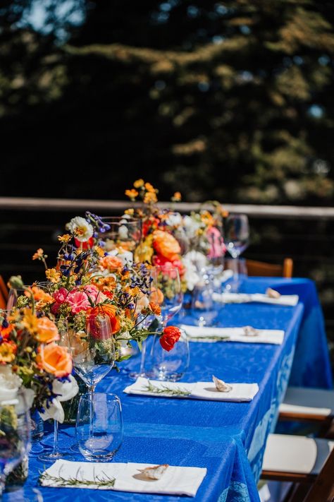 Vibrant-orange-pink-and-red-flowers-against-a-cobalt-blue-table-cloth- Blue Table Cloth, Cobalt Blue Weddings, Indigo Wedding, Pink And Red Flowers, Red Wedding Decorations, Big Sur Wedding, Orange Color Palettes, Sea Wedding, Wedding Tablecloths