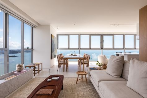 Architect Simara Mello transformed this 236m² beachfront apartment in Balneário Camboriú into a serene family retreat. The minimalist design enhances the panoramic sea view, using natural materials like wood and stone. Custom carpentry, thoughtful lighting, and Brazilian design pieces elevate the space's elegance and comfort. Apartment Sea View, Estilo Clean, Seaside Apartment, Family Of Five, Apartment Architecture, Web Design Studio, Interior Renovation, Glass Facades, Modern Coastal