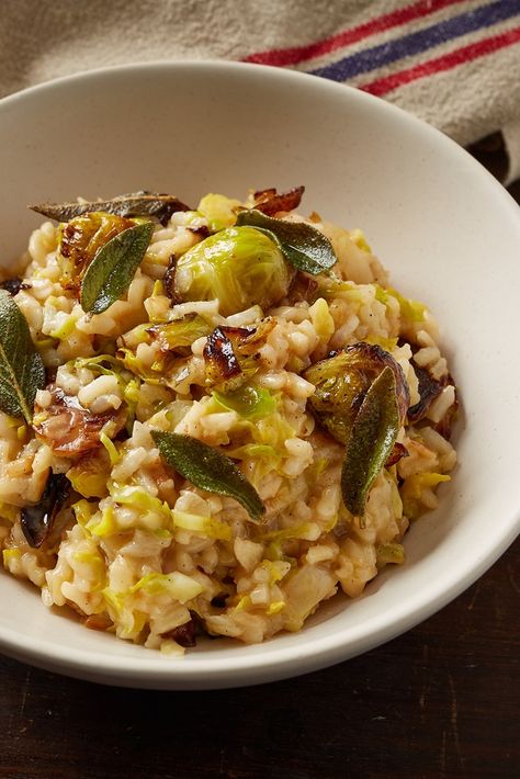 This Brussels sprout risotto recipe is the perfect bowl of comfort food for a chilly evening. Both slow-roasted buttery sprouts and fresh, raw sprouts are folded through creamy rice and topped with crispy sage. It's one of our favourite vegetarian risotto recipes. Brussels Sprout Risotto, Vegan Brussel Sprout Recipes Dinners, Orzo Brussel Sprouts, Brussel Sprout Rice Bowl, Brussel Sprout Risotto, Fresh Sage Recipes, Sage Recipes Fresh, Vegetarian Risotto Recipes, Best Risotto Recipes