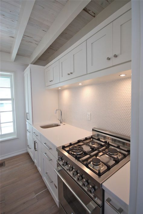 Rosemary Beach, FL - Kitchen with rustic plank ceiling over white shaker cabinets with under cabinet lighting suspended over stainless steel 4-burner stove situated next to prep sink accented with gooseneck faucet and pantry cabinets. Prep Sink Next To Range, White Kitchen Ideas Modern, Cabinet Stove, Architect Ideas, White Subway Tile Kitchen, White Kitchen Cupboards, White Shaker Kitchen Cabinets, Kitchen Table Makeover, White Kitchen Tiles