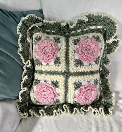 "This Gorgeous, Vintage Style Rose pillow is two sided.  It will have 8 very pretty roses that would be a beautiful accent piece anywhere you chose to display it. The pillow is made using 8 squares, 4 on each side. The border has a generous ruffle around it with a satin ribbon woven all around and tied in a bow in one corner. This one will be made using Caron brand, Simply Soft yarn, in soft Pink, Off White, and Green leaves with a Ribbon trim. It can be made in any other color combo too. It has Crochet Rose Pillow, Quick Crochet Blanket, Roses Au Crochet, Granny Square Crochet Patterns Free, Rose Pillow, Confection Au Crochet, Crochet Pillows, Crochet Flower Tutorial, Crochet Pillow