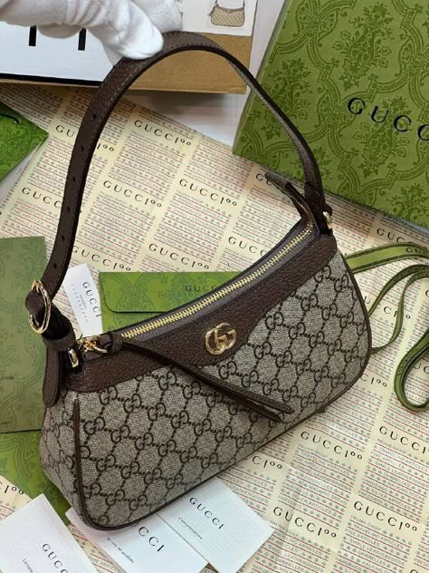 House collections continue the idea that pieces should be timeless and not just in fashion for one season. Guccio Gucci's everlasting monogram continues to enrich new designs with a logo feel. This Ophidia small handbag is presented in the historical GG Supreme canvas, complete with the Double G hardware. Beige and ebony GG Supreme canvas Brown leather trim Cotton linen lining Double G Adjustable top handle with 7.5" drop Top zip closure 9.8"W x 5.9"H x 2.5"D Gucci Ophelia Bag, Designer Hand Bags, Cute Designer Bags, Designer Bags Aesthetic, Designer Purses, Designer Bag, Designer Bags, Shoulder Bags, Gucci Ophidia Bag