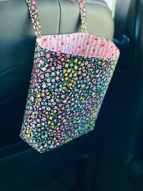 "Looking to add a bit of personality to your ride?  A handcrafted reusable fabric car bag is a decorative way to keep your vehicle clean and clutter free.  Fabric bag holds cell phones, accessories, receipts, snacks, keys, grocery/shopping bags, trash, etc. Also consider hanging in the home or office on doorknob/hook to store most anything.  Makes a wonderful wheelchair bag. Exterior and interior fabric is 100% cotton and interfaced with medium weight interfacing to add extra durability.   Machi Car Trash Can Sewing Pattern, Car Trash Bag, Sewing To Sell, Cute Sewing Projects, Grocery Shopping Bags, Tote Bags Sewing, Cute Car Accessories, Car Trash, Car Bag