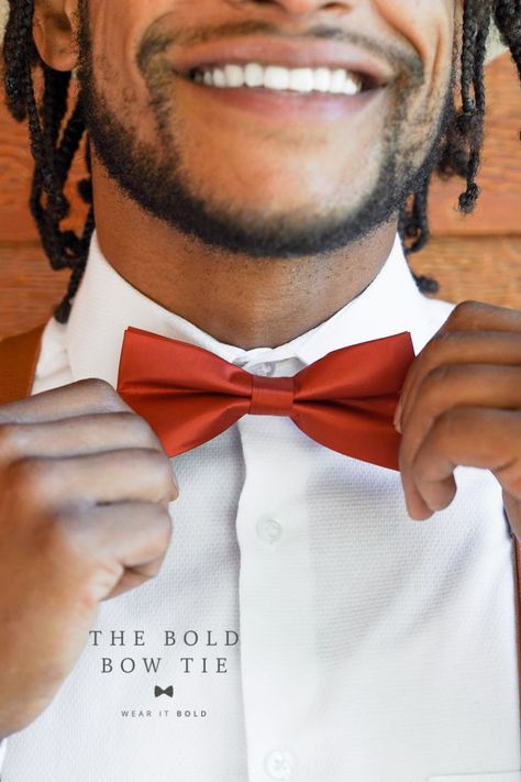 A black man smiles and wears a white shirt. He also wears a shiny sienna bow tie. Burnt Orange Bow Tie, Family Photos Wedding, Wedding Ring Bearer Outfit, Orange Wedding Decorations, Orange Bow Tie, Orange Wedding Themes, Orange Wedding Invitations, Toddler Bow Ties, Burnt Orange Weddings