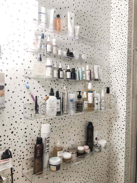 Bathroom with clear ledge shelves displaying and storing skincare products. Clear Floating Shelves Bathroom, Clear Acrylic Shelves Bathroom, Makeup Organization Wall Shelves, Acrylic Shelves In Bathroom, Bathroom Facial Organization, Acrylic Bathroom Storage, Clear Shelves Bathroom, Skincare Wall Shelf, Skincare Shelves Bathroom