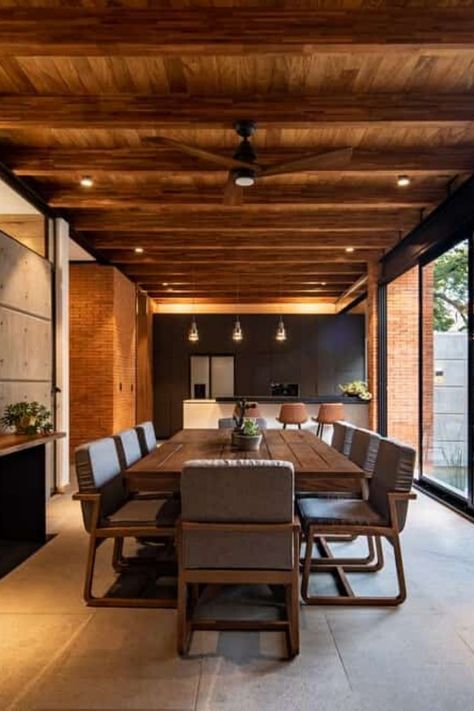 This contemporary dining room uses a mix of minimalist, boho and rustic interior design. The large rustic dining table is paired with modern boho dining chairs. Decor includes indoor plants. Wooden ceiling fan hangs from the wood panel exposed beam ceiling. The tiled flooring has a stone finish. Tap to see more mix decor ideas, other home decor ideas, and more of the interior of this luxurious custom home. #diningroom #customhome    Architecture: Di Frenna Arquitectos Photography: Onnis Luque Large Rustic Dining Table, Filipino Interior Design, Dining Room Ceiling Fan, Exposed Wood Ceilings, Boho Dining Chairs, Tiled Flooring, Beam Ceiling, Wooden Ceiling Design, Wooden Beams Ceiling