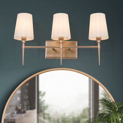 Inject new energy to your bathroom, powder room, or bedroom with this 3-light vanity light. Supported by a rectangular backplate with horizontal arms, this fixture features brass finishes and white fabric shades, which brings modern charm to your cozy home. No matter what style your room is, the simple and classic vanity light is a perfect choice for you. Plus, the dimmer switch and dimmer bulbs (not included) are recommended to satisfy your different vibe needs. | House of Hampton® Amer 3-Light Mirror Sconces, Brass Vanity Light, Vanity Light Bar, Transitional Vanity, Arched Mirror, Indoor Wall Sconces, Bathroom Vanity Light, White Vanity Bathroom, Gold Bathroom