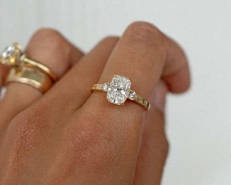 A gorgeous recent custom piece, with a 2.06 elongated cushion cut dimond, 2 round diamond accent stones, set into a low band flat band for a modern feel ✨ Details: - 2.06ct elongated cushion diamond - 2x round diamonds - 18k yellow gold - 2mm wide shank #elongatedcushion #customengagementring #engagementringideas #engagementringdesign #threestoneengagementring #nz #aus Engagement Rings Flat Setting, Cushion Cut Engagement Ring With Thick Band, Elongated Cushion Cut 3 Stone Ring, Cushion Ring Stack, Cushion Cut Elongated Engagement Ring, Cushion Elongated Engagement Ring, Engagement Ring Old Money, Small Elongated Cushion Engagement Ring, Rounded Cushion Engagement Ring