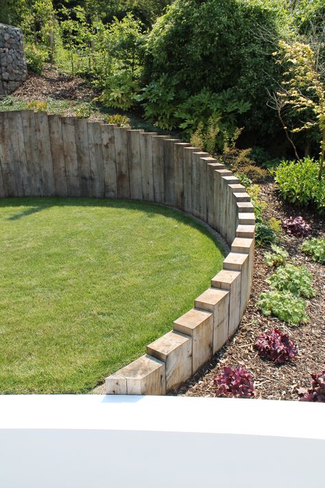 Oak sleepers are used through out the project, set vertically to follow organic curves, retain ground and blend different levels within the garden. Curved Retaining Wall Garden, Railway Sleepers Garden Retaining Walls, Sloping Front Garden Ideas, Curved Garden Wall Ideas, Railway Sleepers Retaining Wall, Sleeper Ideas For Garden, Garden Design With Sleepers, Curved Sleeper Wall, Levels Garden Ideas