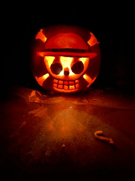 Glowing pumpkin in a dark room with the straw hat luffy logo skull and cross bone Luffy Pumpkin Carving, Luffy Pumpkin, Pumpkin Anime Carving, One Piece Pumpkin, Gojo Pumpkin Carving, Naruto Pumpkin Carving, One Piece Pumpkin Carving, Anime Pumpkin Carving Ideas, Pumpkin Carving Ideas Anime