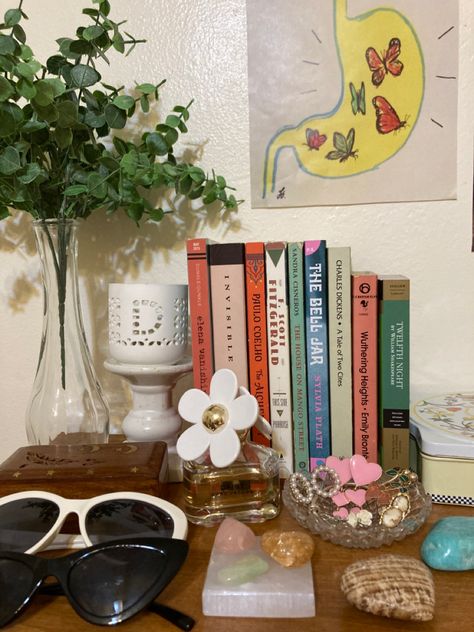 Picture of decor on top of dresser with various books, plant, crystals, jewelry, perfumes, and sunglasses Crystals Book, Book Bedroom, The House On Mango Street, Sandra Cisneros, Books Bookshelf, Emily Bronte, Twelfth Night, The Bell Jar, Aesthetic Room Decor