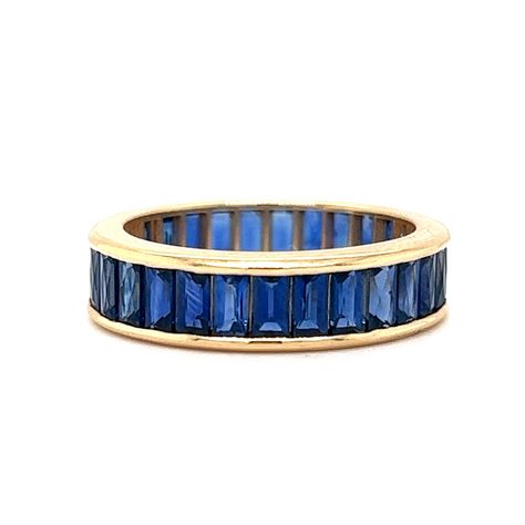 French Cut Blue Sapphire Eternity Band in 18k Yellow Gold A glamourous, modern stacking band in bold blue sapphires! This French Cut Sapphire eternity band is finished in 18 karat yellow gold. This sleek stacking ring features 5.51 total carats of French cut blue sapphires set in a channel around the entire band. Streamlined with scintillating color. This gemstone ring is a jewelry designer's dream.  A colorful band to check off your search for Something Blue. Primary Stone: Natural Blue Sapphire Shape and Measurements: 3.70 mm x 2.70 mm x 1.80 mm = .19 ct (29) Stone Weight: 5.51 ct General Characteristics: Height Above Finger: 2.15 mm Measurements: 5.12 mm Total Gram Weight: 4.1 g Ring Size: 6.0 Resizable: No Era: Modern 1970-Present -- ALL PIECES ARE SUBJECT TO PRIOR SALE DUE TO HAVING A Blue Sapphire Eternity Band, Ombre Rings, Pave Diamond Wedding Bands, Sapphire Eternity Band, Sapphire And Diamond Band, Contour Wedding Band, Sapphire Wedding Band, Half Eternity Wedding Band, Sapphire Band