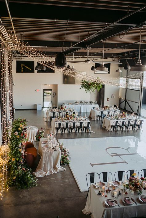 Sparkling lights hang from the ceiling of our industrial wedding venue while tables are set for reception with bone-colored linen and colorful florals Loft Wedding Reception, Event Space Decor, Industrial Wedding Reception, Industrial Modern Wedding, Hangar Wedding, Event Venue Design, Event Space Design, Modern Industrial Wedding, Industrial Wedding Decor