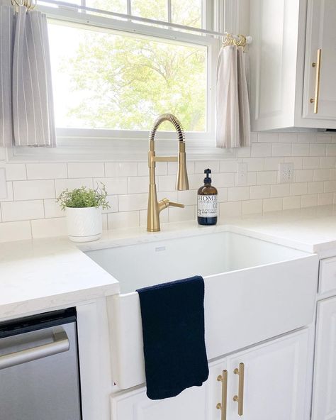 This white modern kitchen boasts a golden faucet that complements the white sink. The use of a white color scheme with gold accents creates a chic and minimalistic style. Place a mini potted plant by the sink to add a pop of green to the space. White Kitchen Sink Gold Faucet, Gold Faucet Kitchen, White Farm Sink, Modern Vintage Kitchen, Traditional Farmhouse Kitchen, Farmers Sink, Kitchen 2023, White Farmhouse Sink, Gold Faucet