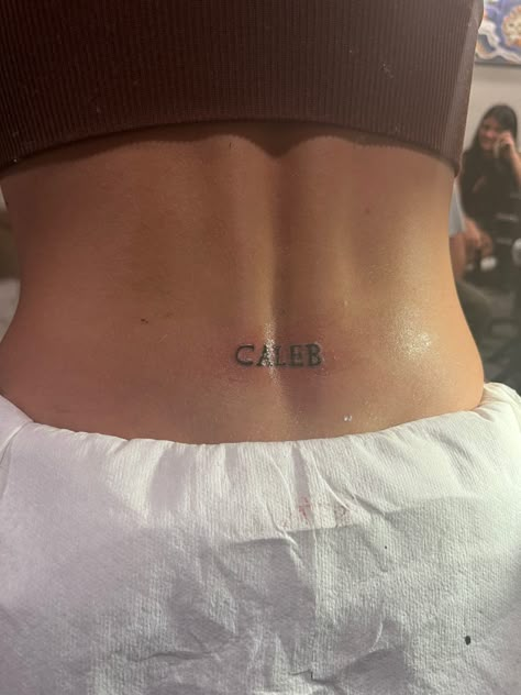 Girly Word Tattoos, Back Mini Tattoo, Letter Tramp Stamp, Cute Dainty Tramp Stamp, Trampstamp Tattoo Words, Lower Back Name Tattoos, Spine Tattoo With Tramp Stamp, Spine And Tramp Stamp Tattoo, Lucky You Tramp Stamp