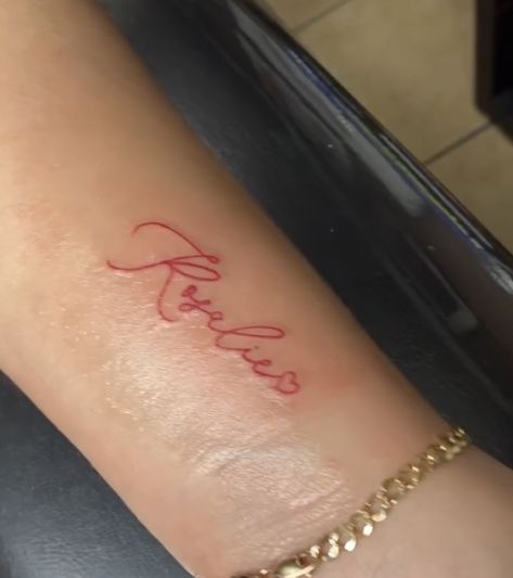 Red Ink Tattoos Wrist, Loved Ones Name Tattoo, Name Tattoos Red Ink, Cute Name Tattoos For Women, Red Name Tattoo, Red Script Tattoo, Last Name Tattoo For Women, Small Red Tattoo, Cute Name Tattoos