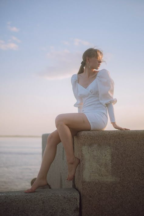 Woman in Dress Sitting on Rock against Blue Sky · Free Stock Photo Feminine Sitting Poses, Dress Poses Sitting, Sitting On Wall Pose, Woman Sitting Reference, Lady Sitting Pose, Beach Model Photoshoot Poses, Women Sitting Poses, Female Sitting Pose Reference, Carefree Photoshoot