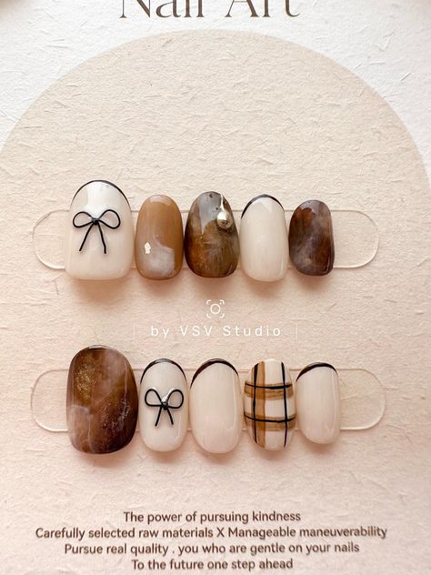 This nail set blends sophistication with a touch of rustic charm. The brown and off-white nails feature a soft ombre effect, creating a natural and earthy vibe. The French tips in off-white add a refined, classic touch, while the black, handcrafted wire bow accentuates the elegance of the design. Each blend of colors is unique, ensuring that every set is one-of-a-kind. Perfect for those seeking a chic yet organic look, this set brings a delicate balance of simplicity and artisanal craftsmanship White Brown Nails Design, Trendy Winter Nails 2024, Nail Art Detailed, Classic Elegant Nails, Brown Bow Nails, Autumnal Nail Designs, Brown Ombre Nails Acrylic, Aesthetic Autumn Nails, Soft Autumn Nails