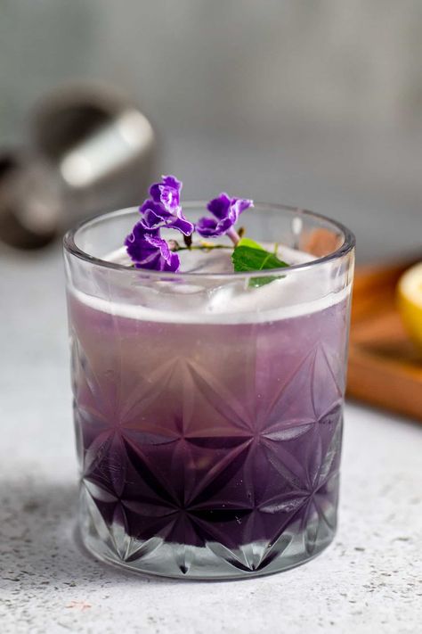 one glass of purple rain cocktail with ice and purple flowers Purple Rain Drink, Purple Rain Cocktail, Rain Cocktail, Blue Gatorade, Grape Vodka, Blueberry Gin, Vodka Recipes Drinks, Unique Appetizers, Sparkling Lemonade