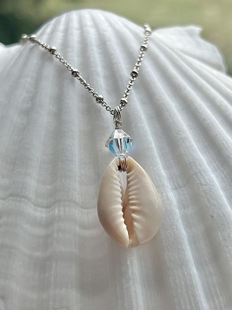 Genuine Cowrie Shell & Swarovski Crystal necklace  ~ Made from a 100% genuine handpicked cowrie shell found off the shores of Oahu, Hawaii.  The cowrie shell pendant has been silver wire wrapped and strung on a .925 Sterling Silver Satellite Chain. Attached with Sterling Silver findings to an 18 inch chain with a spring ring clasp closure. The necklace has an "Of the Sea" oval brand tag at the closure. This shell pendant is a medium size and a great every day necklace! It's dainty and beautiful! Looks great worn alone or paired with your favorite necklace layers!  We do recommend removing your jewelry before showering or while going swimming to help preserve the quality of your special piece!  This necklace is the perfect gift for our ocean loving souls, charged with the special energy and Every Day Necklace, Necklace Layers, Cowrie Shell Necklace, Necklace Shell, Tarnished Jewelry, Necklace Bead, Swarovski Crystal Necklace, Cowrie Shell, Shell Necklace