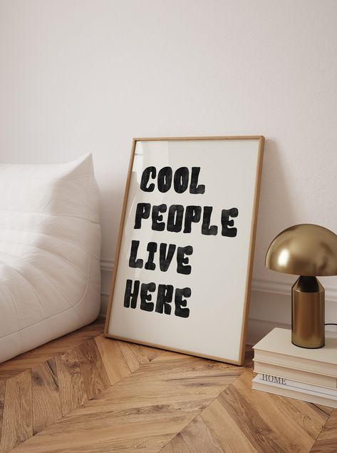 Add a fun and modern touch to your space with this "Cool People Live Here" typography wall art. Featuring bold black text in a minimalist design, this Scandinavian-inspired poster is perfect for creating an inviting atmosphere in any room. The clean, stylish font and uplifting message make it an ideal addition to your living room, entryway, or office. With its high-quality print and contemporary look, this poster celebrates positive vibes and cool spaces in a subtle yet impactful way. Cool People Live Here Poster, Typography Wall Art, Black Text Poster, Uplifting Wall Art, Minimalist Poster, Living Room Decor, Scandinavian Art Print, High Quality Wall Art, Fun Home Decor, Modern Typography Art, Positive Message Print, Stylish Wall Art, Contemporary Home Decor, Minimalist Black Poster, Tren Wall Art Living Room Minimalist, Living Room Minimalist, Scandinavian Art Print, Text Poster, Room Minimalist, Trendy Wall Decor, Cool People, Print Typography, Office Poster