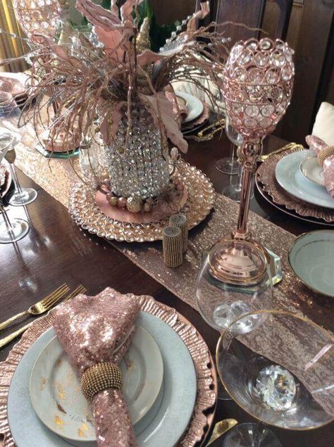 Decorate your dining table with rose gold décor accents for a contemporary & glamorous look. Spread a rose gold sequin runner in the center of your dining table and set a rose gold charger plate in the center to place a crystal-beaded vase on top. Arrange goblet candle holders atop hexagonal mirrors for a charming appeal and elevate your place settings by folding rose gold sequin napkins into gold rings and place them atop marble plates & rose gold reef chargers. Rose Gold And Silver Centerpieces, Rose Gold Tea Party Table Settings, Rose Gold Plates Table Settings, Rose Gold Dining Room, Rose Gold Christmas Table Setting, Rose Gold Table Decorations, Rose Gold Christmas Table, Rose Gold Table Setting, Dining Table Arrangements