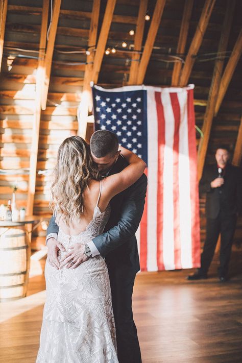 An American flag waves behind the bride and groom for the first dance of their military wedding. #weddingphotos #virginiawedding #barnwedding #weddingreception #rusticwedding #farmwedding #weddingvenue #48fields #weddingideas #firstdance #militarywedding #southernwedding #countrywedding Army Wedding Ideas, Army Wedding Pictures, Military Wedding Army, Red White Blue Wedding, Americana Wedding, Military Background, Army Wedding, Wedding Flags, Patriotic Wedding