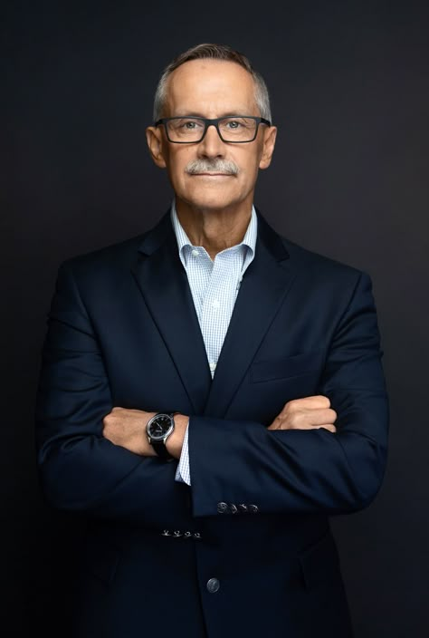 Business headshot of mature man wearing glasses with arms crossed smiling. Suit Portrait, Pastor Headshots, Studio Corporate Portrait, Headshots For Pastor, Mens Photos, Standing Headshot Poses Men, Corporate Photography Men, Corporate Photography Poses, Corporate Shoot Ideas