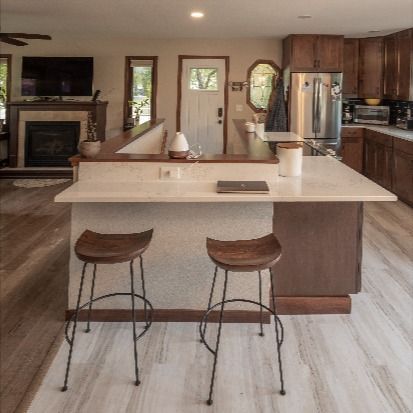 When your staircase is in the entryway, butting up into your kitchen, creating open concept is a challenge. For this remodel, we opened up the staircase and wrapped the kitchen counter around it to create a functional island while allowing for an open concept flow throughout the main level. Check out the before photo to see how boxed in this space felt before we got our hands on it! Kitchen Island With Stairs To Basement, Kitchen With Stairs In Middle, Stairs Under Kitchen Island, Kitchen Island Meets Staircase, Stairs In Kitchen Layout Open Floor, Kitchen Next To Stairs, Open Stairs In Kitchen, Open Concept With Stairs In Middle, Open Basement Stairs In Kitchen